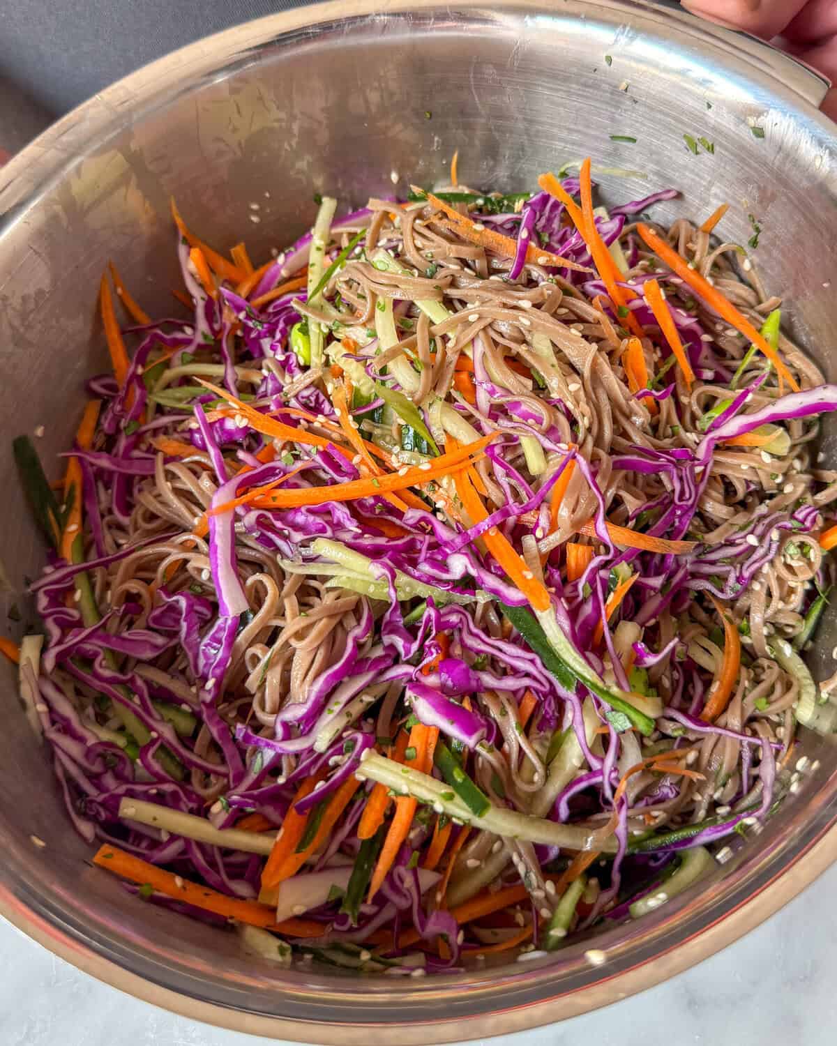 Toss the vegan soba salad with dressing.