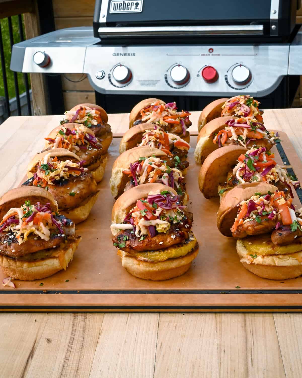 A tray with assembled chicken teriyaki sliders in rows.