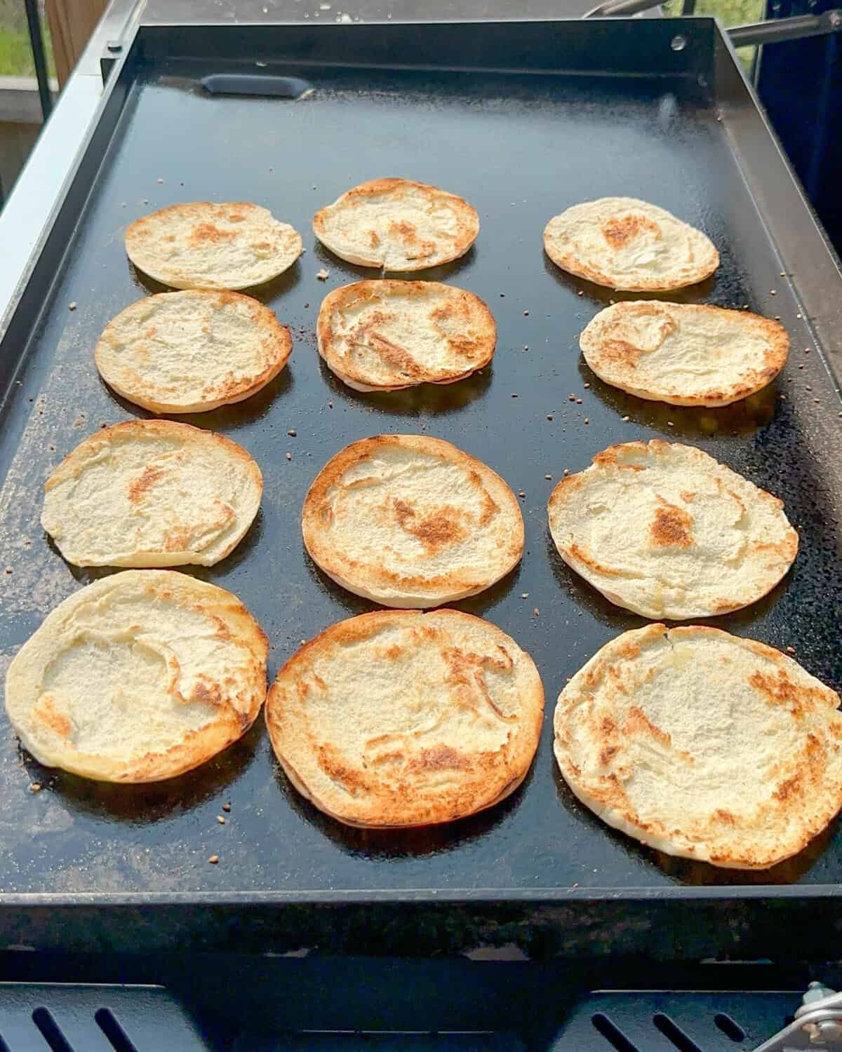 Toasted mini pita halves on a griddle.