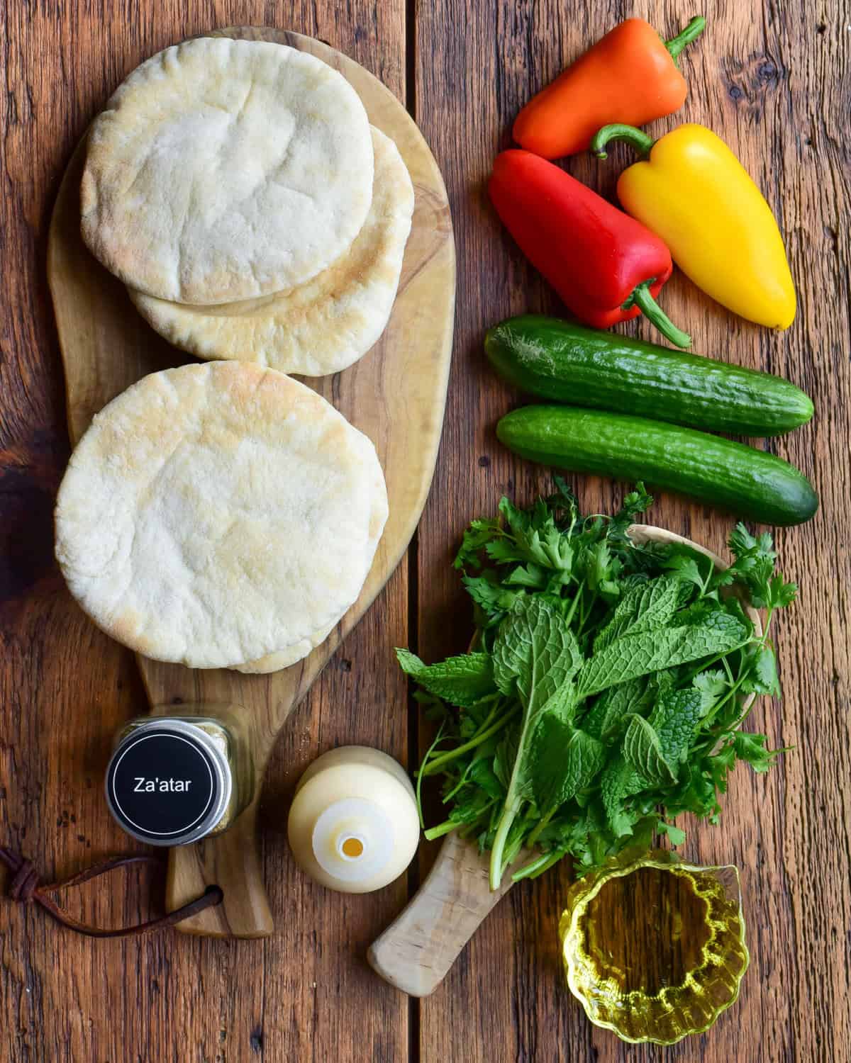 Pitas, fresh veggies, herbs, spices and sauce for a lamb smash slider recipe.