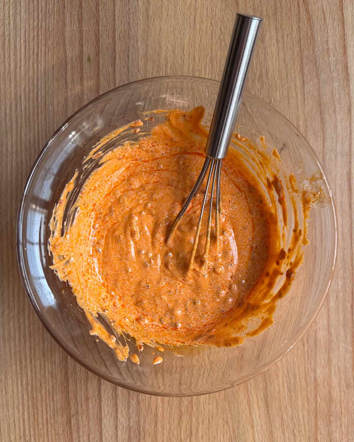 A bowl of spicy harissa yogurt for lamb smash burgers.