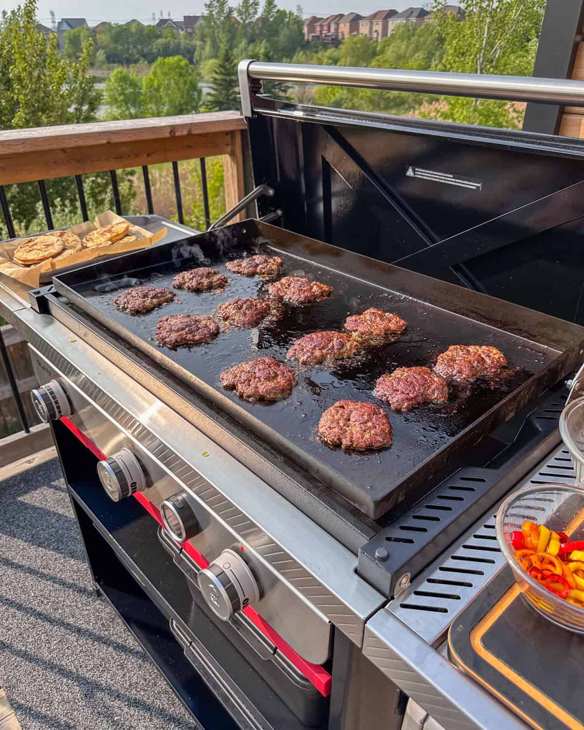 Twelve smashed cooked lamb patties on a griddle for smash sliders.