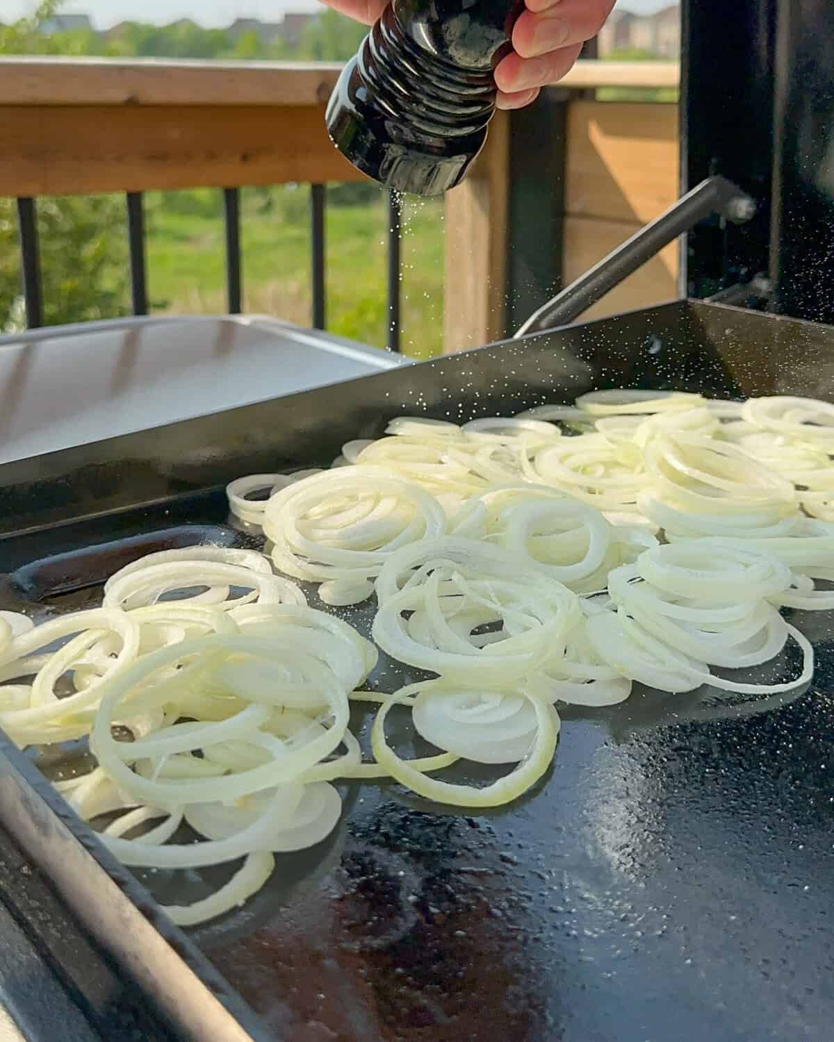 Onions on a flat top grill are about to get griddled.