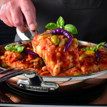 Lifting a piece of poached halibut out of a skillet.