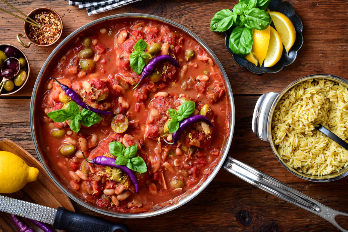 Four pieces of fish poached in tomato sauce and served with orzo.
