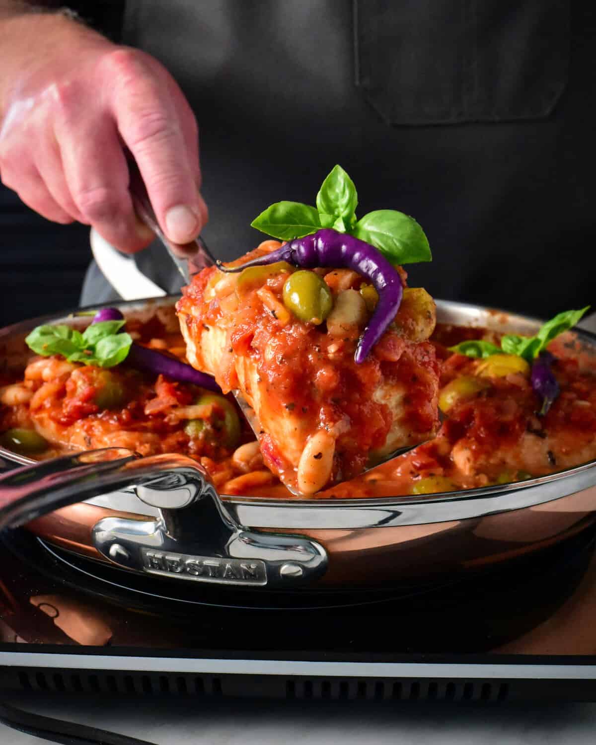 Lifting a piece of poached halibut out of a skillet.
