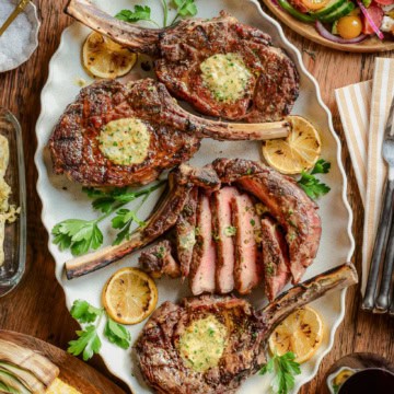 Four grilled veal chops on a platter served family style.