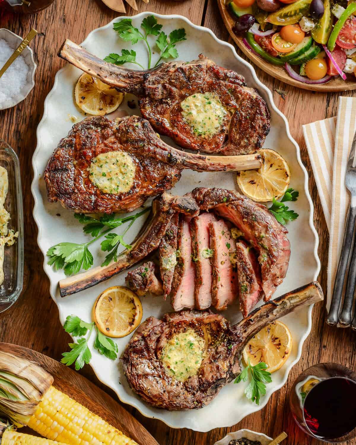 Four grilled veal chops on a platter served family style.
