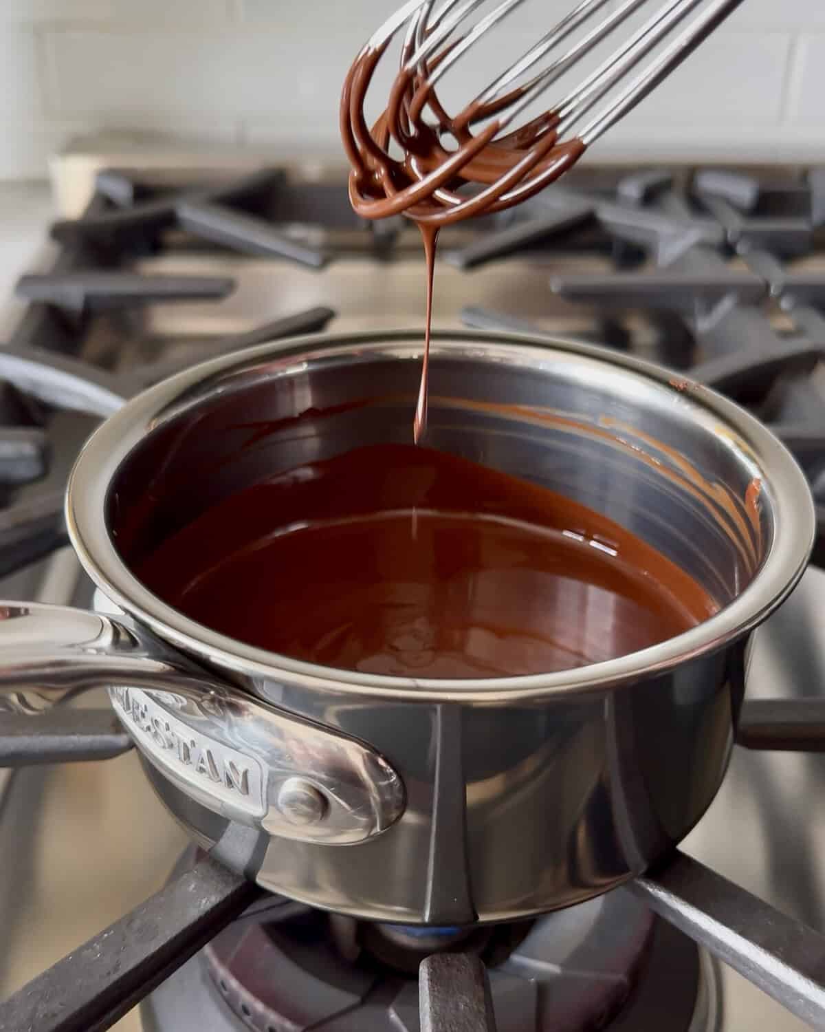 Melted dark chocolate drizzle in a small pot.