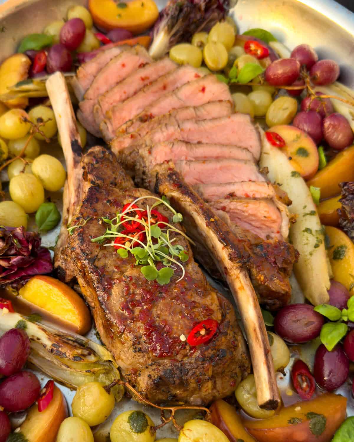 Two diavola veal chops, one sliced and one unsliced. Served with roasted grapes and peaches.