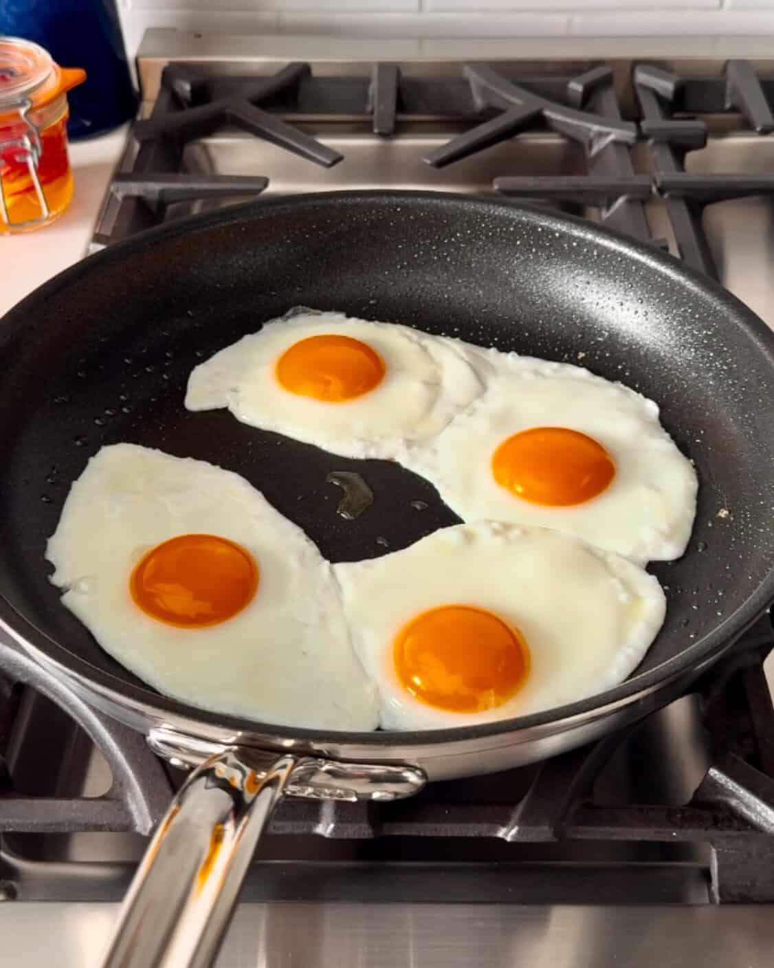 Four eggs are frying in a pan.