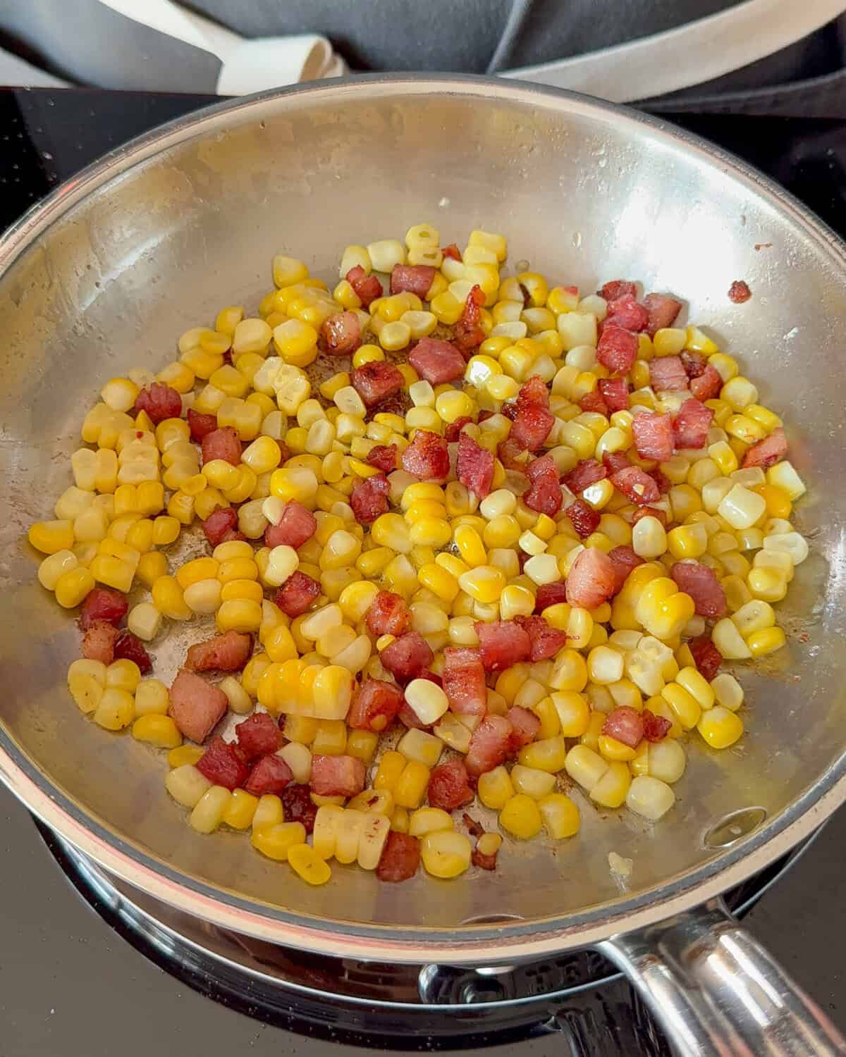 Pancetta and corn are getting cooked for seared scallops with corn.