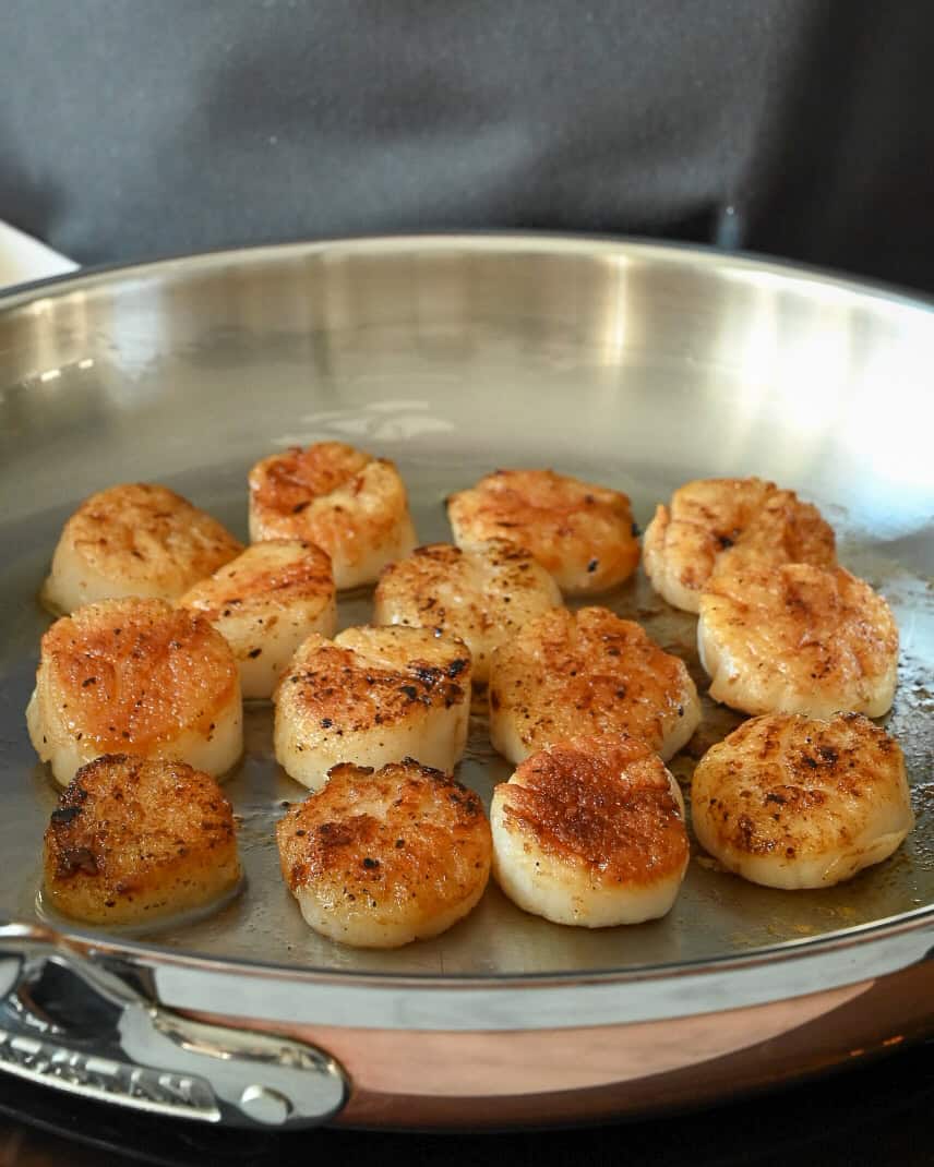 A skillet with seared scallops in a skillet.