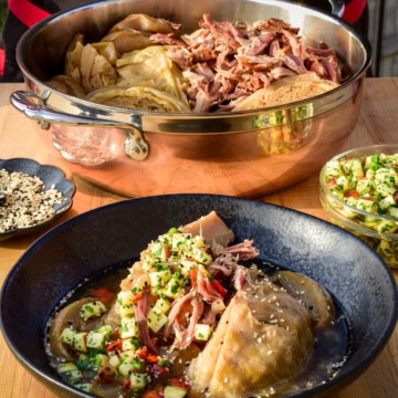 A copper pot filled with cider-braised cabbage and ham, served in a bowl with an apple gremolata.