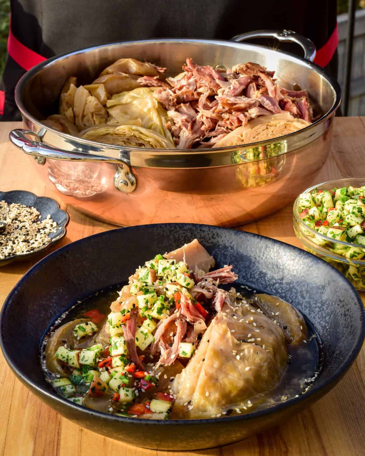 A copper pot filled with cider-braised cabbage and ham, served in a bowl with an apple gremolata.