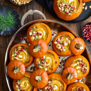 An oval pan with several mini pumpkins served with a creamy pumpkin soup. Served with toppings, plus more on the side.
