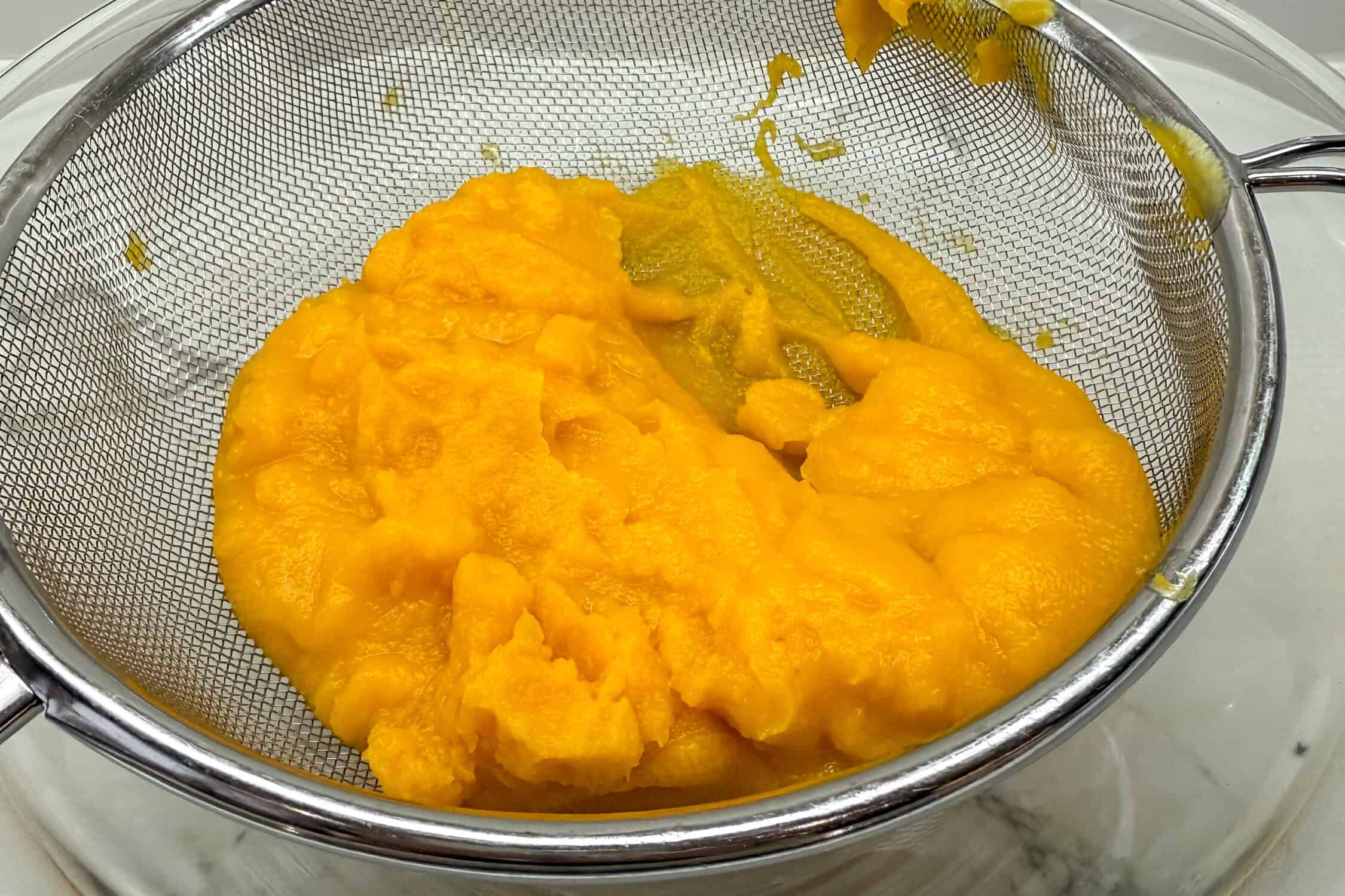 Drain excess moisture from the pumpkin puree using a sieve.