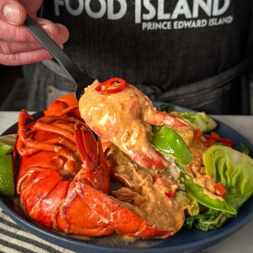A plated coconut curry lobster with veggies and rice.