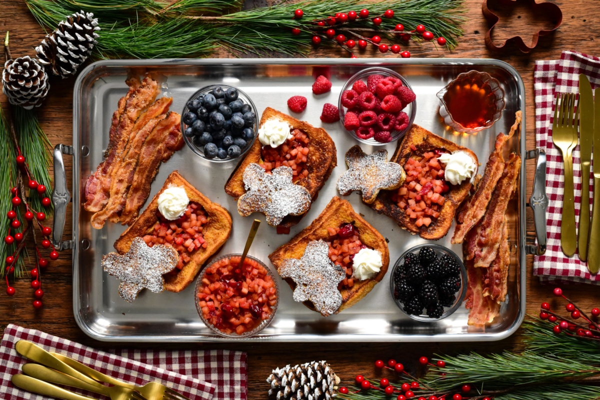 Gingerbread French Toast with Apple Cranberry Compote served with fresh berries and bacon. Topped with whipped cream and dusted with icing sugar.