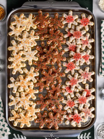A baking sheet with three rows of differently decorated glazed snowflake sugar cookies.
