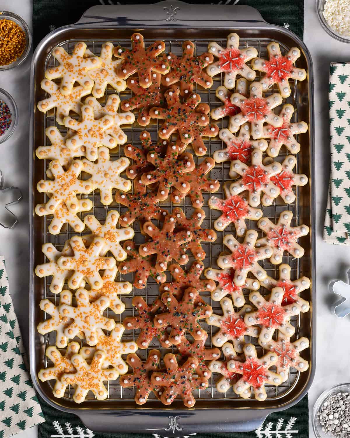 A baking sheet with three rows of differently decorated glazed snowflake sugar cookies.