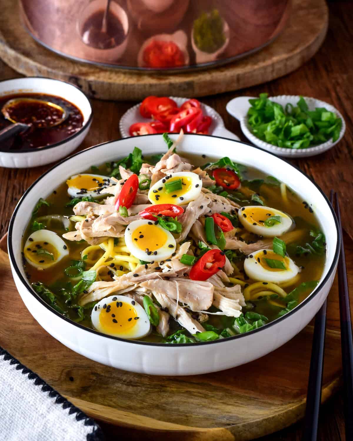 A bowl of ginger chicken ramen soup with bok choy, ramen-style noodles and jammy quail eggs.