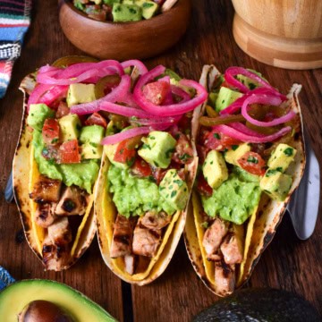 Three citrus marinated grilled pork double decker tacos in a stand.