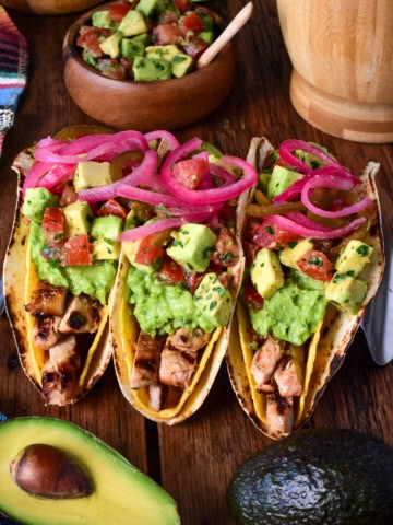 Three citrus marinated grilled pork double decker tacos in a stand.
