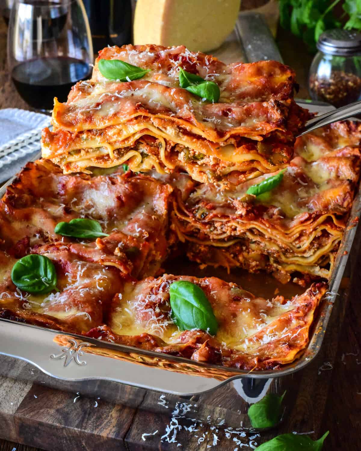 A baking pan with a sausage and beef lasagna and a slice being lifted out to reveal the layers.