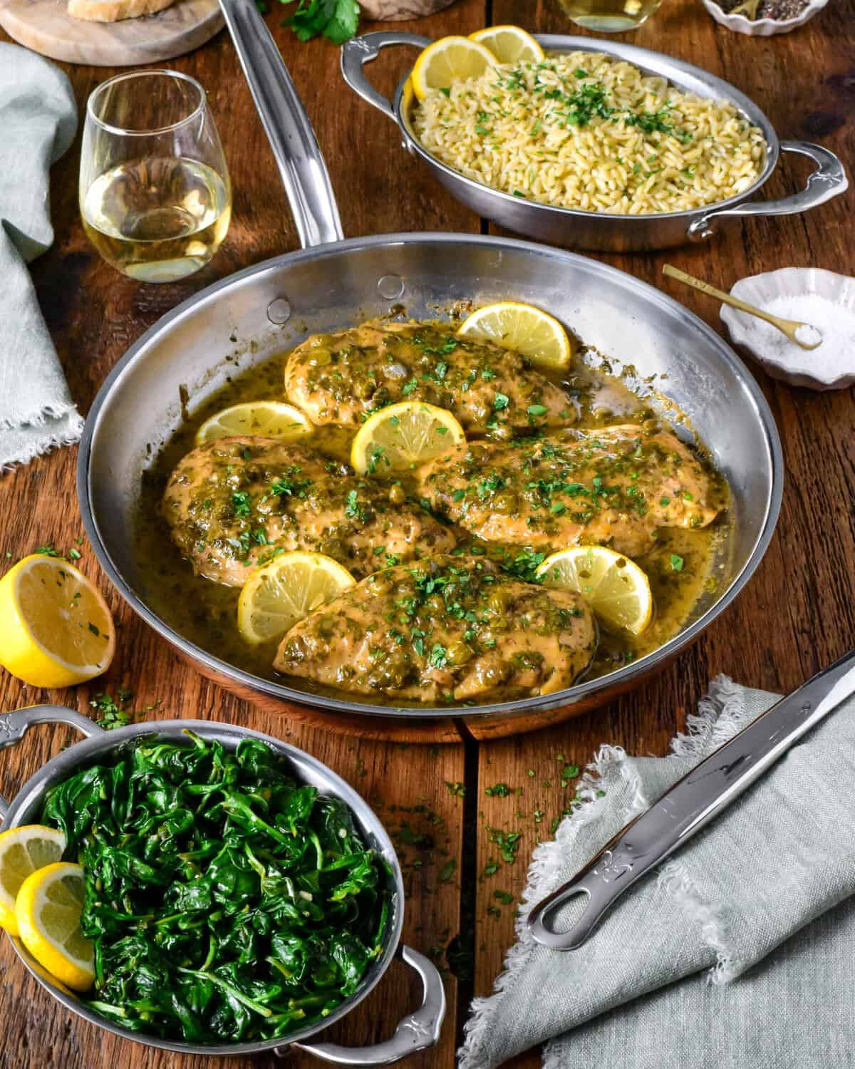 A skillet of lemony chicken picatta is served with orzo and spinach.
