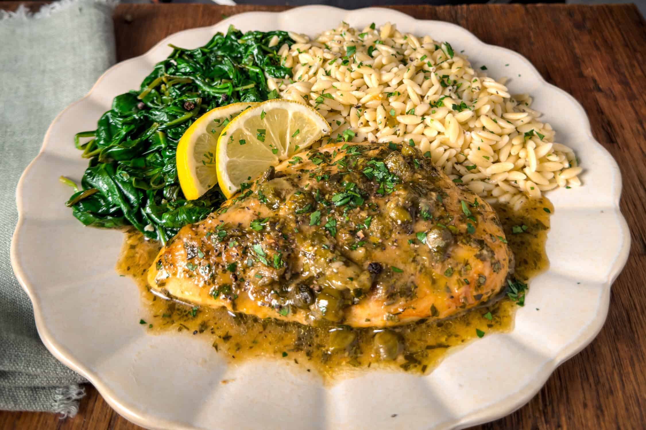 Chicken piccata served with orzo and spinach.
