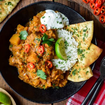 A bowl of beef and vegetable coconut curry served with basmati rice, coconut rice and garlic naan.