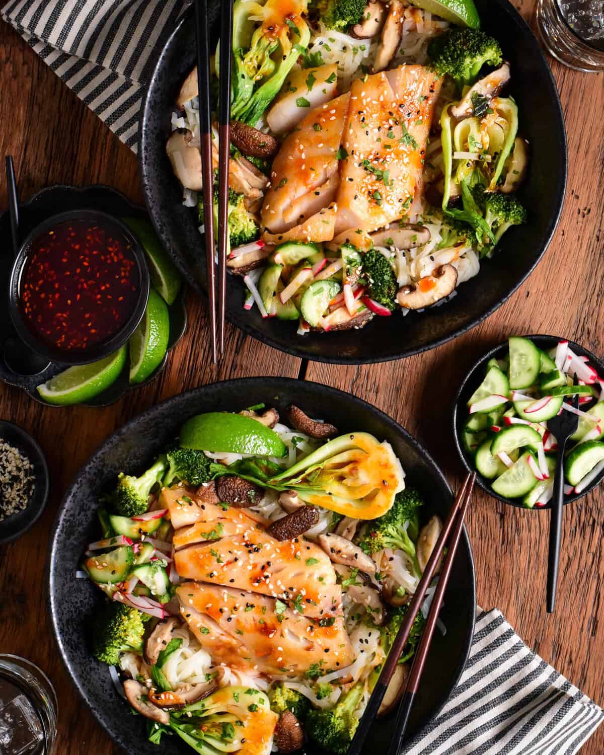 Two bowls of miso black cod served with rice noodles and vegetables.