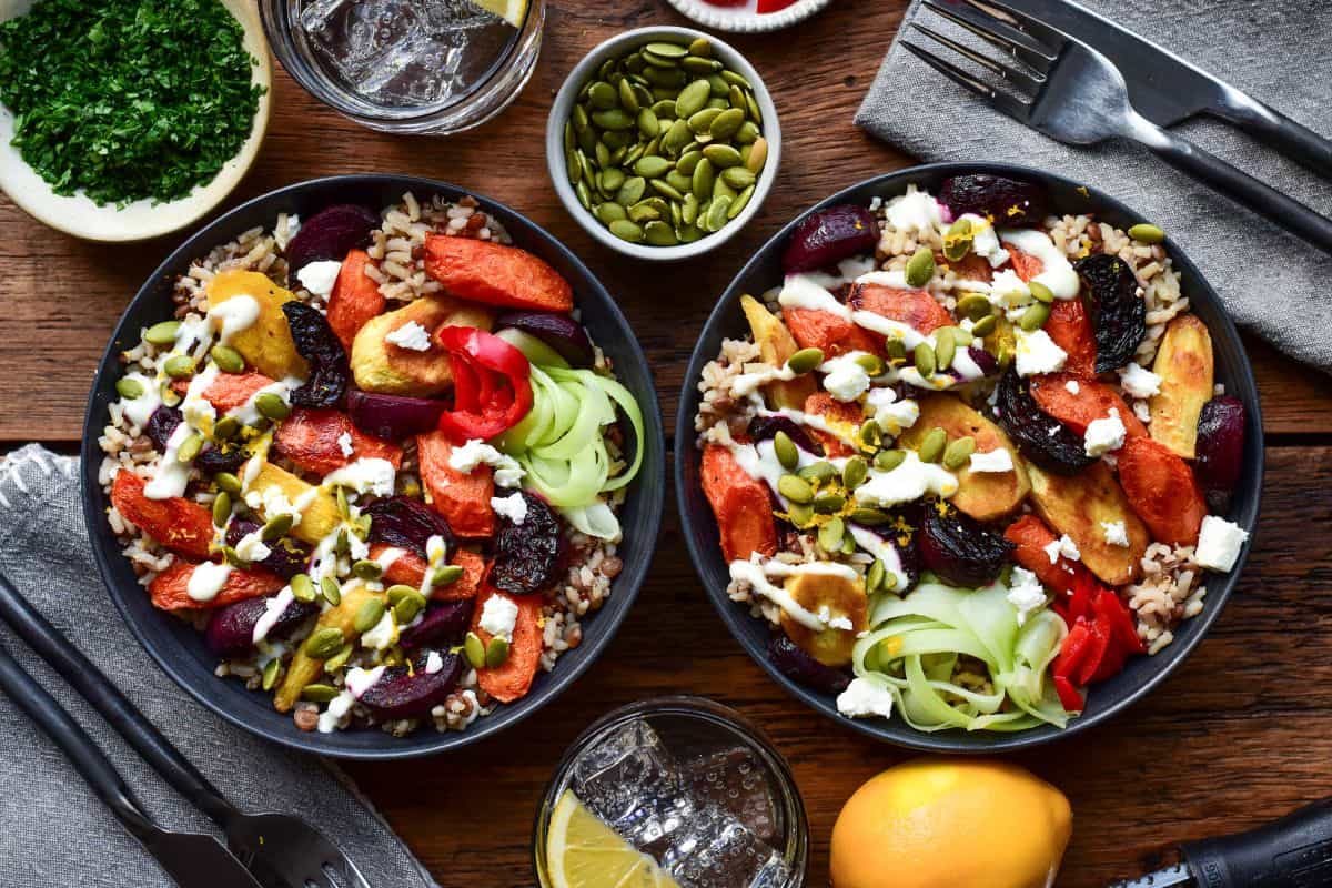 Two Winter Root Vegetable Bowls topped with Lemon Yogurt Dressing and pepitas.