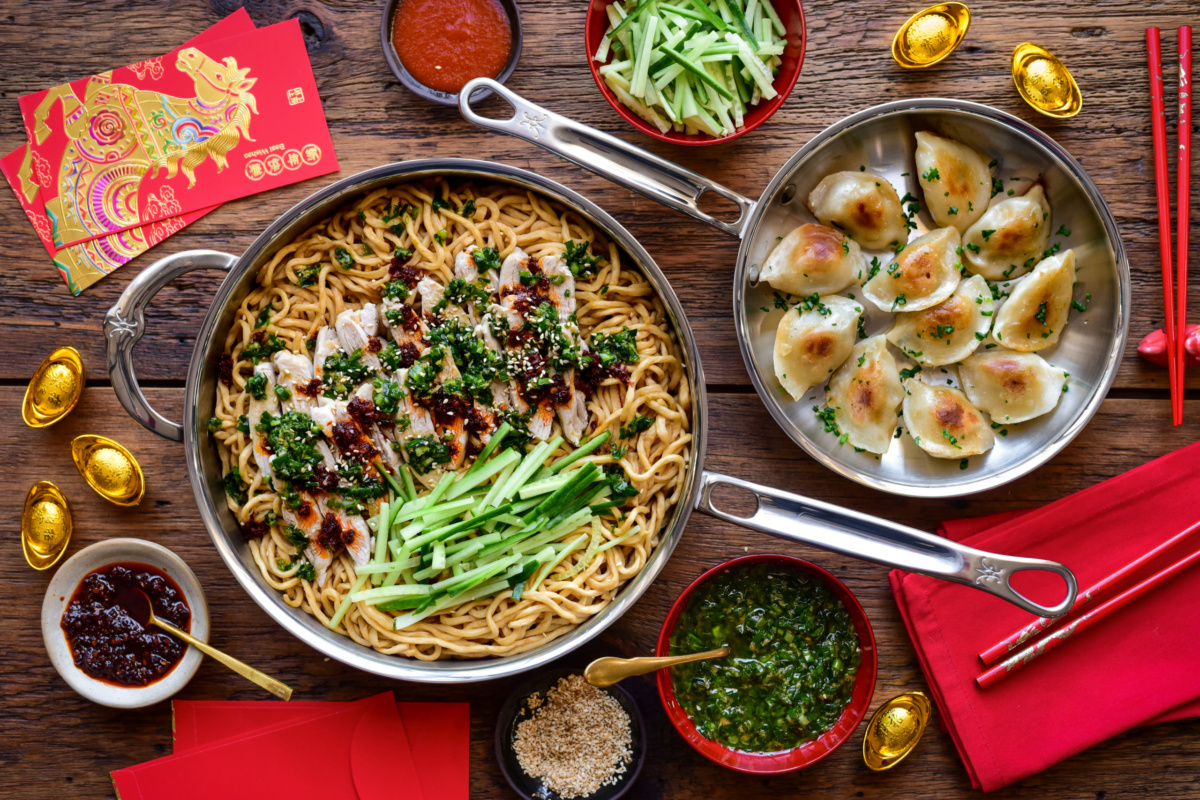 A Lunar New Year spread of Yi Mein noodles with ginger chive chicken and a skillet of dumplings.