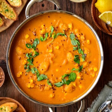 A large pot of butter bean and carrot soup that is topped with microgreen.