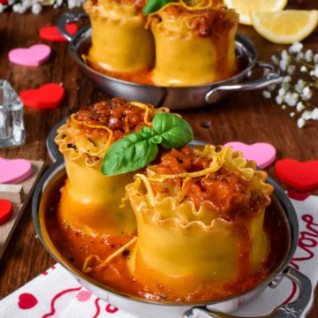 Two individual seafood lasagna roll ups with a lobster bisque sauce served in au gratins for Valentine's Day.