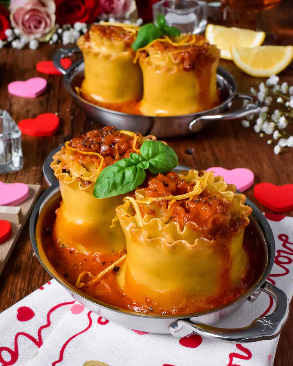 Two individual seafood lasagna roll ups with a lobster bisque sauce served in au gratins for Valentine's Day.