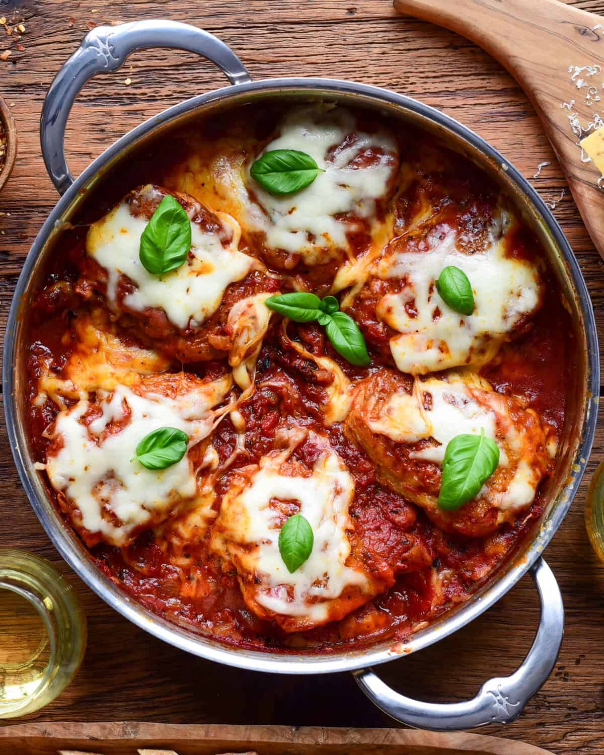 Tomato braised chicken parm thighs topped with melted cheese and fresh basil.