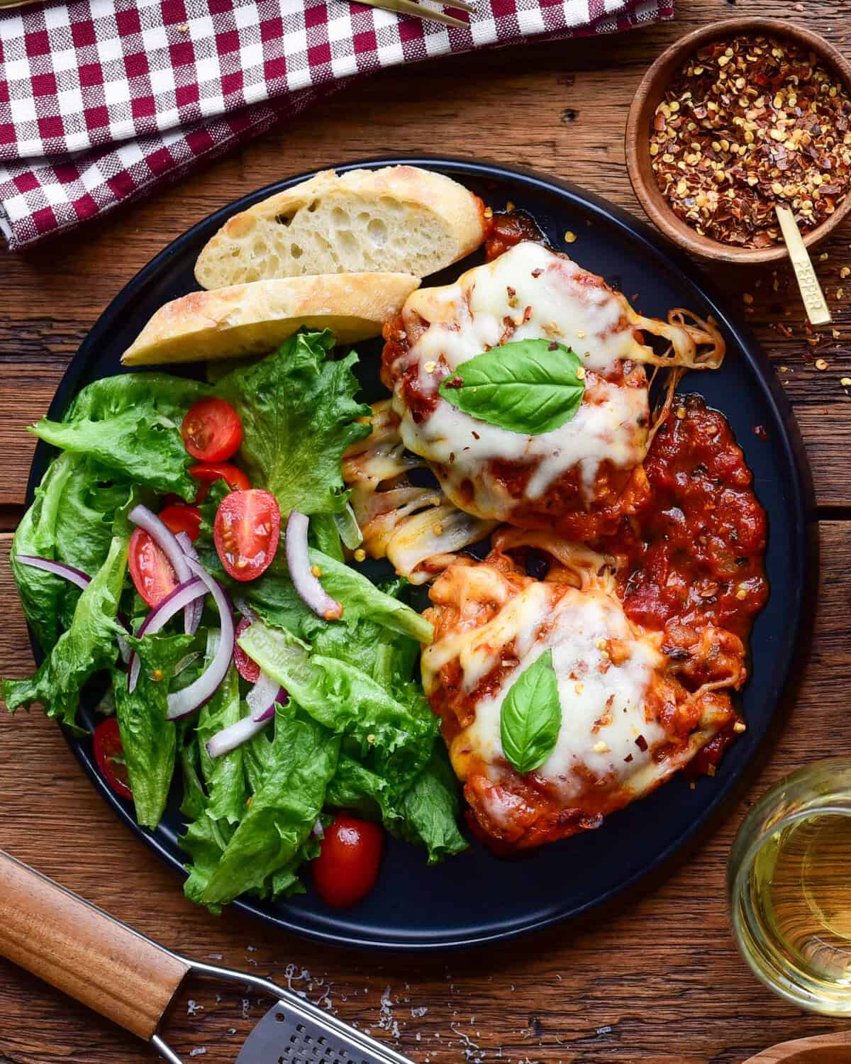 Tomato braised chicken parm thighs served with a fresh green salad and bread to soak up the sauce.
