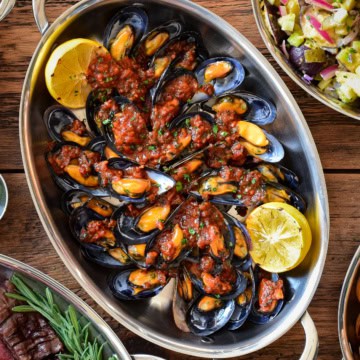 Mejillones en Salsa Picante Spanish Mussels on Half Shell served in an oval au gratin with grilled lemon wedges.
