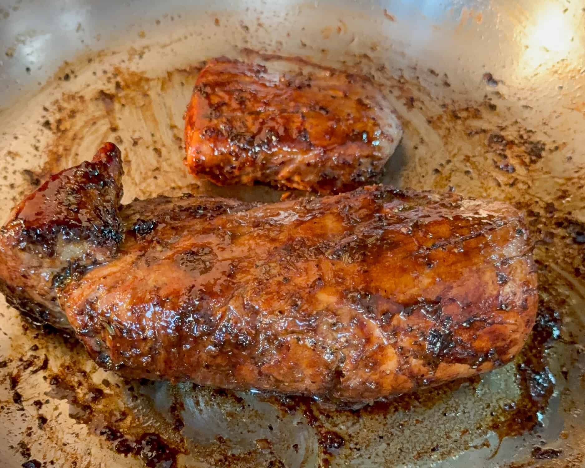 Beautifully carmalized pork tenderloin in a skillet.