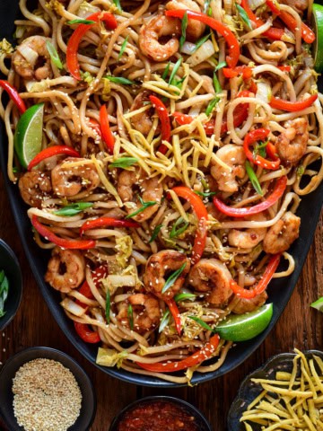 A platter of Sticky Soy Argentinian Shrimp & Fried Ginger Udon. Served with extra fried ginger, limes, sesame seeds and green onions.