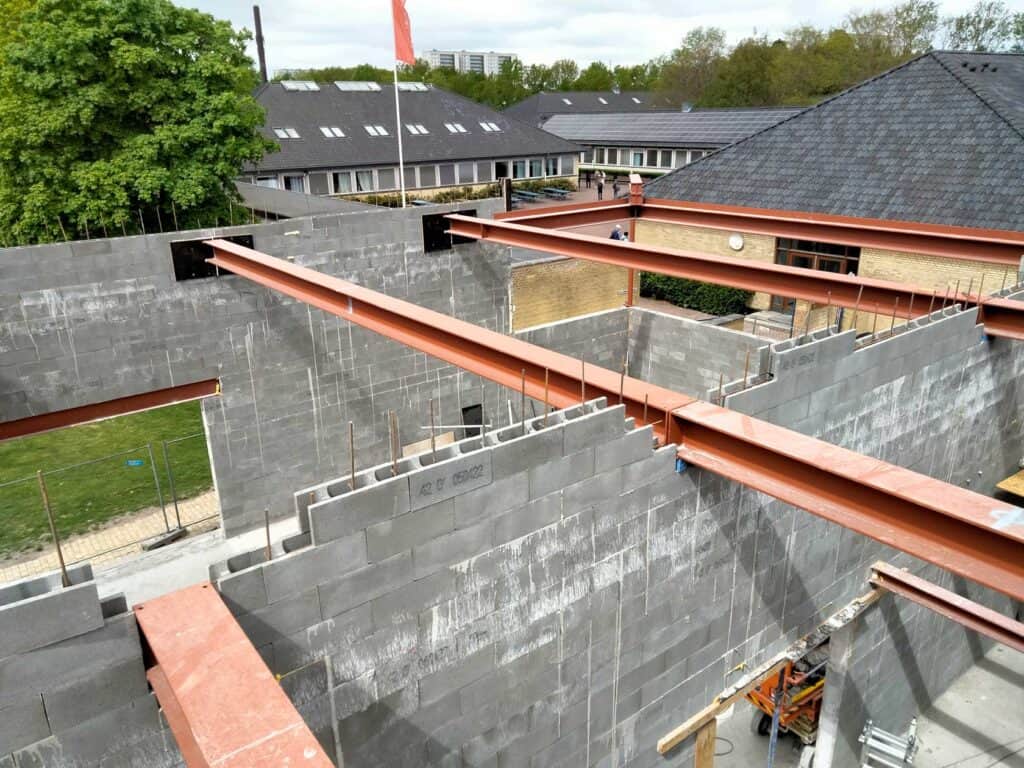 Overblik over rødbrune I-bjælker i stål lagt ud som bærende elementer på vægge af fundablokke. Leveret og monteret af Albertslund Smede- og Maskinværksted.
