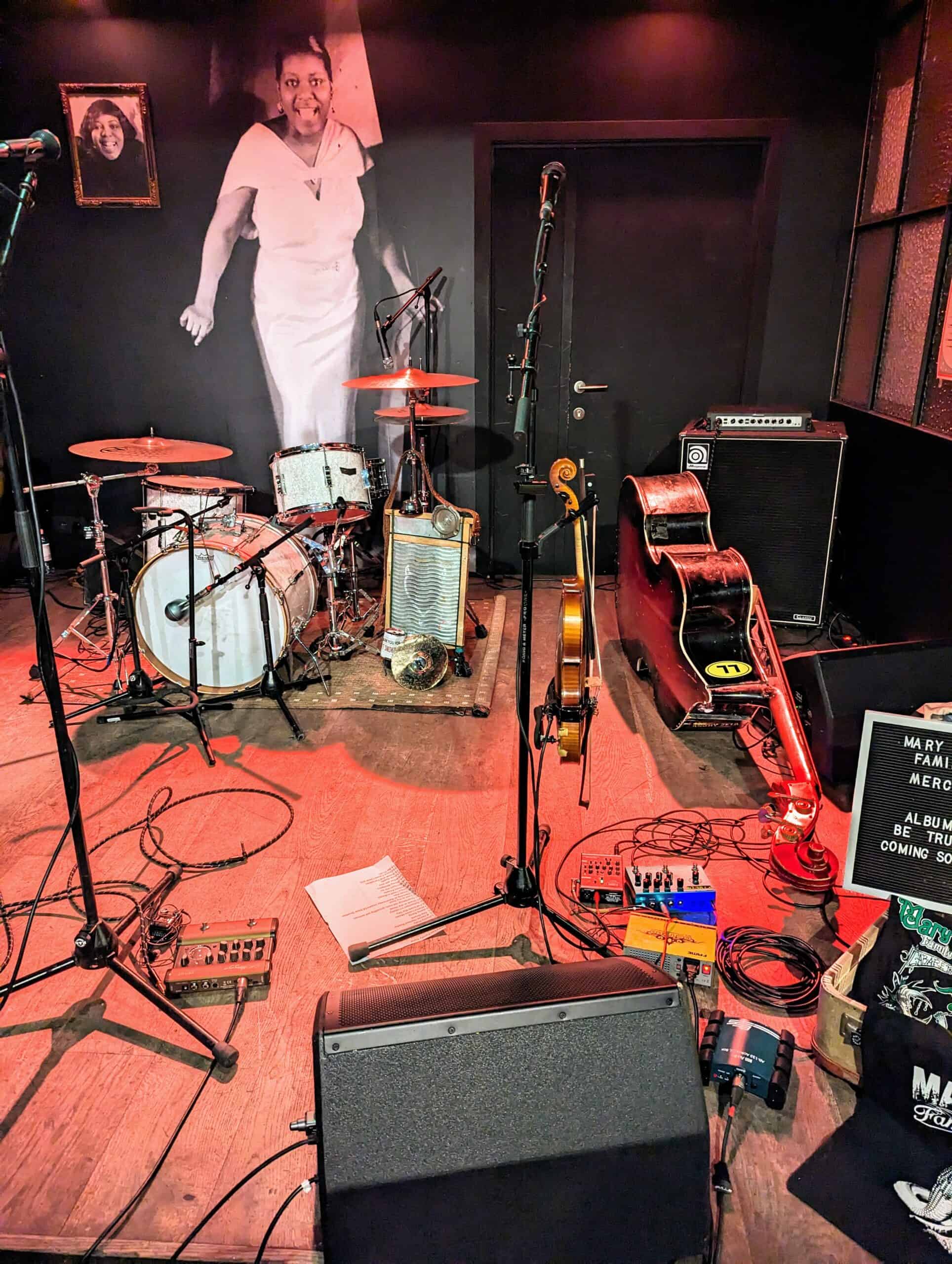 Joining a band means sharing a crowded stage with other who share your love of music. Here is a crowded stage with drums, bass, fiddle, speakers, cables.
