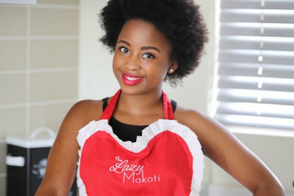 African woman entrepreneur smiling in a modern kitchen setting.