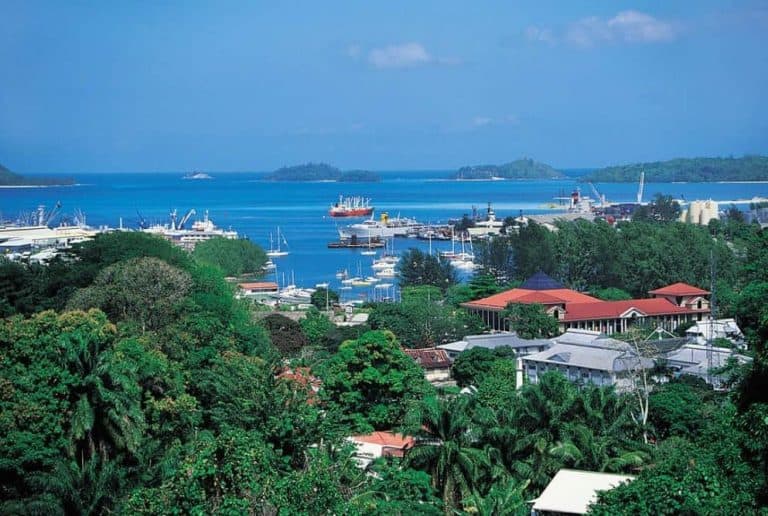 Scenic view of Seychelles coastline with boats and lush greenery.