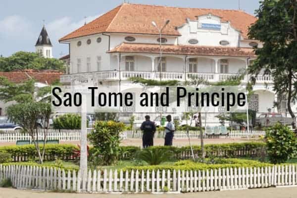 Colonial-style building in Sao Tome with lush gardens and white picket fence.