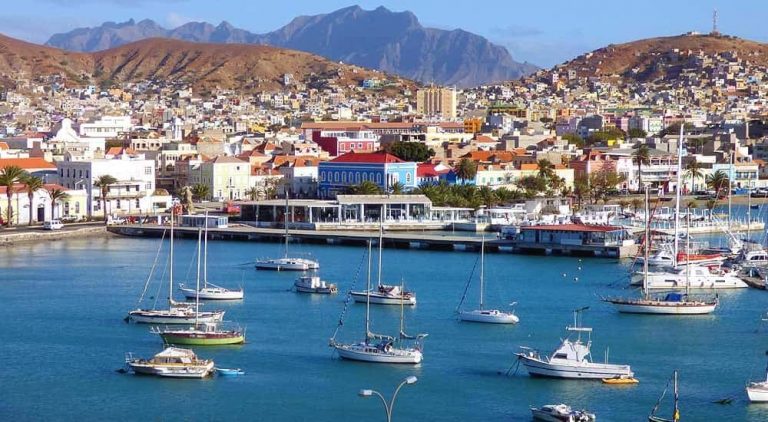 Scenic view of Cape Verde harbor with boats and colorful city buildings.