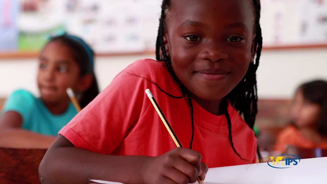 Young African girl smiling in classroom during International Women's Day celebration.